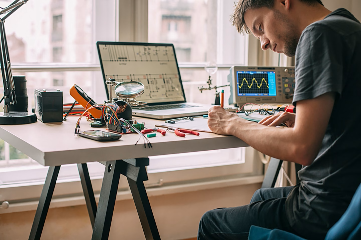 Engineer working on embedded systems with electronic components and oscilloscope
